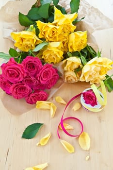 Fresh yellow and pink roses on wooden background