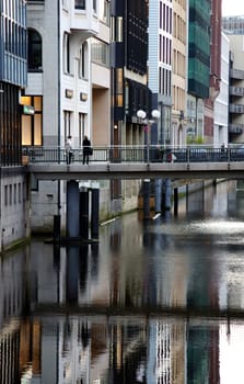 Hamburg,Germany – January 02,2014: Two unknown women cross a bridge over a canal in which Hauser are reflected on January 2,2014 in Hamburg.