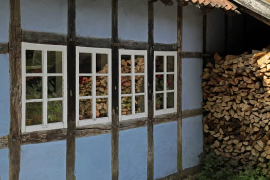 Blue half-timbered house and stack of firewood