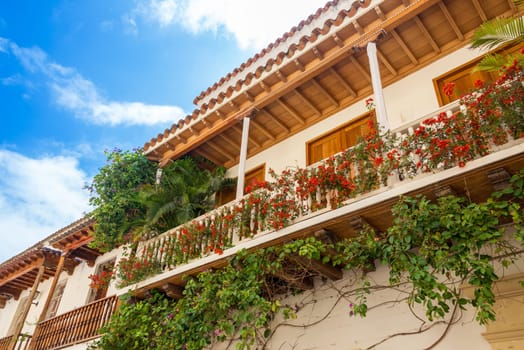 White colonial balcony in historic Cartagena, Colombia with red flowers on it