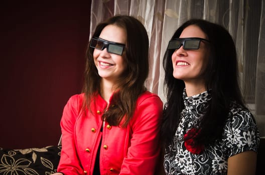 Two beautiful women at home watching a 3D movie