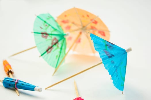 Different colors of cocktail umbrellas on a white background.