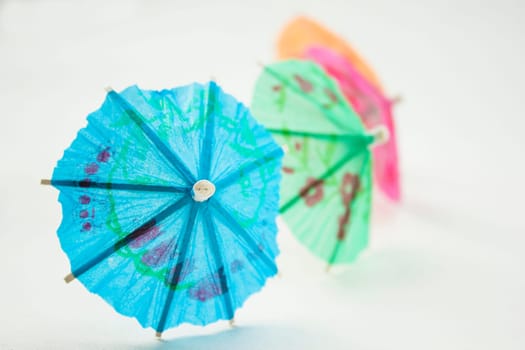 Different colors of cocktail umbrellas on a white background.