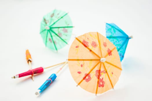 Different colors of cocktail umbrellas on a white background.