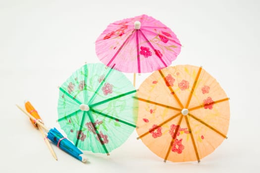 Different colors of cocktail umbrellas on a white background.