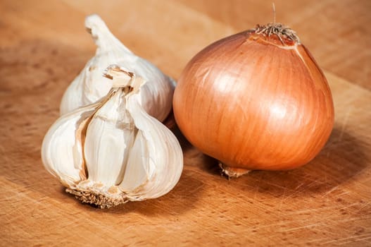 Bulbs of onion and garlic on wooden surface