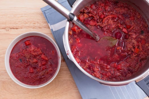 Bowl and pan of borscht soup with ladle.