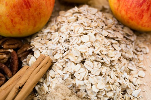 Oats and cinnamon sticks with pecans and apples on side.