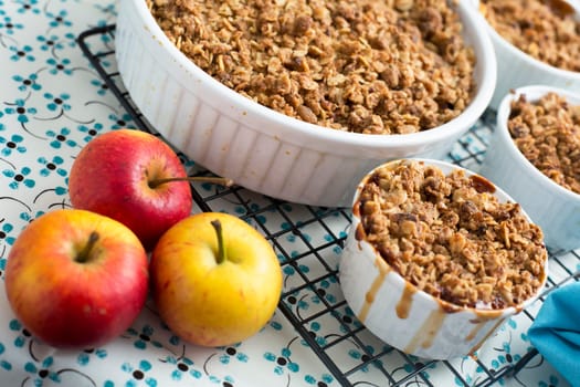 Freshly made apple crumble on cooling rack with apples.