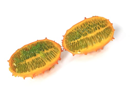 Horned cucumber or kiwnao (Cucumis metuliferus) in longitudinal section exposed against a white background