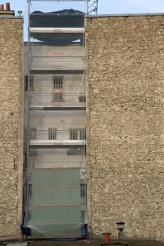 The photograph of a distinctive house façade,in the niche of which stands a scaffolding.