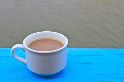 hot coffee in white cup on wooden, During leisure time on river background