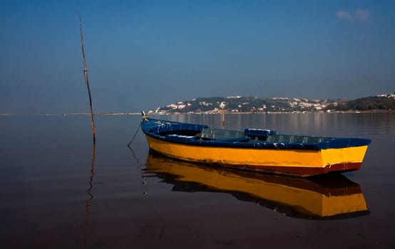 Yellow Wooden fishing boat docked in the bay of Obidos, Portugal