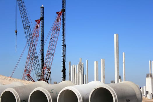 FORT LAUDERDALE, FLORIDA - FEBRUARY 20, 2013: Lots of construction cranes, pylons, rebar, and cement sewer pipes near sandy hills on a sunny day at the Fort Lauderdale-Hollywood International Airport.