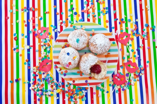 Fresh fritters on a small plate on a colorful striped background
