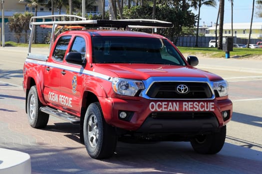 FORT LAUDERDALE, FLORIDA - FEBRUARY 5, 2013: Front and side of a red Ocean Rescue truck facing north parked on a sidewalk along State Road A1A on a sunny winter day.