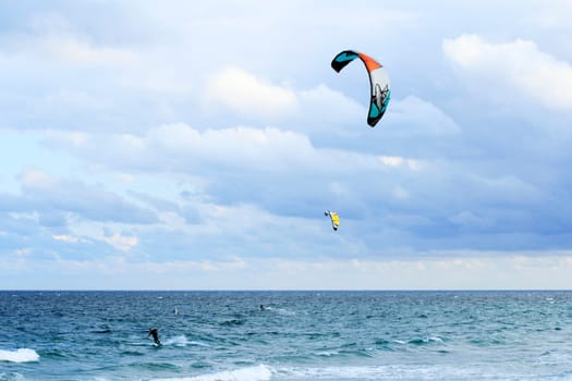 FORT LAUDERDALE, FLORIDA - FEBRUARY 9, 2013: Two kite surfers having fun kiteboarding with colorful kites on the Atlantic ocean on a windy and partly cloudy day winter morning.