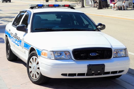 FORT LAUDERDALE, FLORIDA - FEBRUARY 5, 2013: Fort Lauderdale, Florida law enforcement auto seen from the front parked on A1A and people sitting down at an outdoor sidewalk restaurant in the background