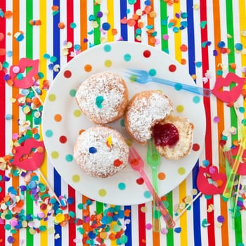 Fresh fritters on a small plate on a colorful striped background