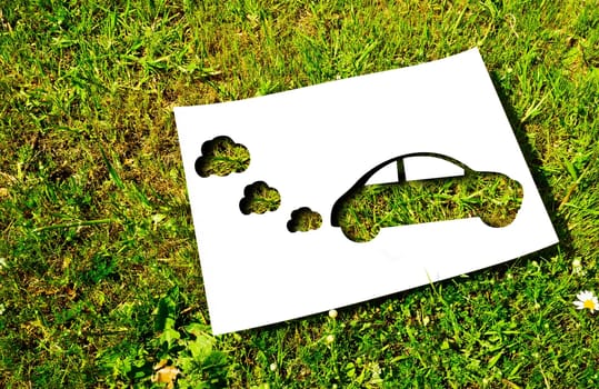 White paper cut in the shape of a car on a background of grass. Renewable energy concept