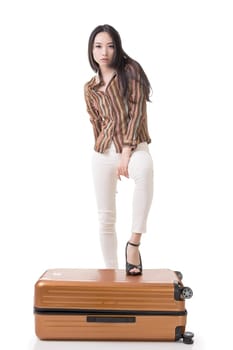 Modern Asian woman stand on a luggage, full length portrait on white background.