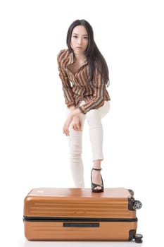 Modern Asian woman stand on a luggage, full length portrait on white background.