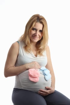 Details of a pregnant woman with baby shoes on her belly and isolated on white background.