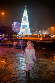 girl against the backdrop of the city's large New Year tree in the evening
