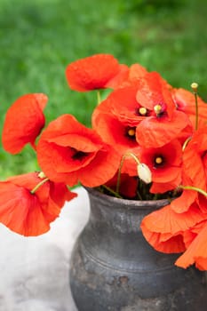 Bouquet of wild flowers of red poppies in an old clay jug. Summer photo, rustic style, close-up