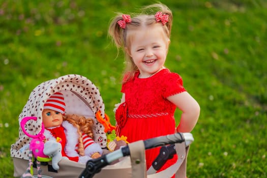 a child with a toy stroller and a doll is playing in nature