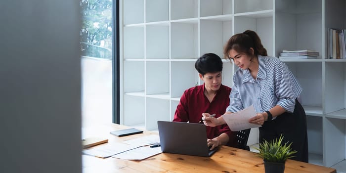 Two Asian businesspeople working discussion business matters at office.