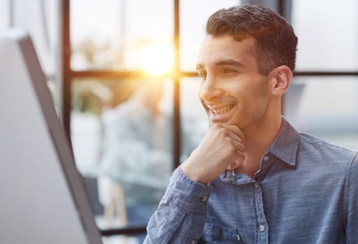 A young pensive man works in the office and thinks about something.