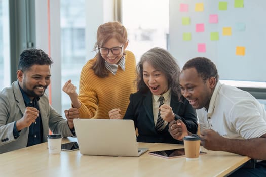 Diverse businesspeople raise hands celebrate after successful investment strategy at office.