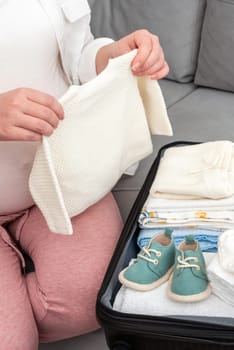 A dedicated pregnant woman arranges her essentials in a suitcase, gearing up for her stay in the