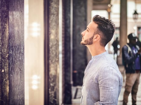 A man standing in front of a shop looking at the shop window in a busy commercial street