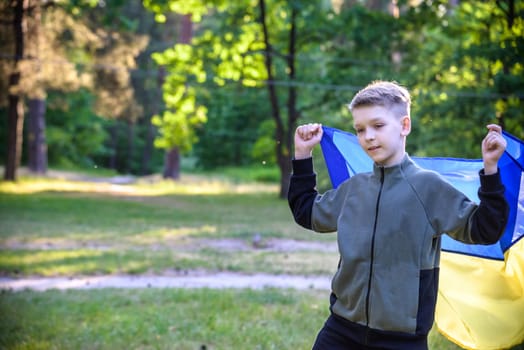 Pray for Ukraine. boy with Ukrainian flag running the summer park. Little kid waving national flag praying for peace. Happy child celebrating Independence Day.