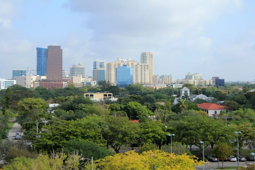 FORT LAUDERDALE, FLORIDA - MARCH 23, 2013: Modern downtown skyline seen on a slightly foggy, hazy morning past a variety of tropical trees. The population of Fort Lauderdale in 2012 was 170,747.