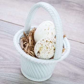 Three colorful bright Easter eggs in a basket on a wooden table Easter decoration custom spring festive