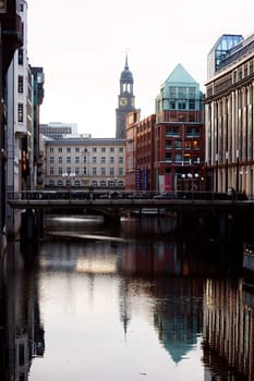 Hamburg,Germany – January 02,2014: Unknown people cross a bridge over a canal in which houses are reflected on January 02,2014 in Hamburg.