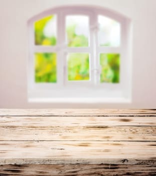 Empty scrubbed clean rustic wooden kitchen table under a pretty white domed window with cottage panes in a country kitchen ready for your cooking ingredients or product placement