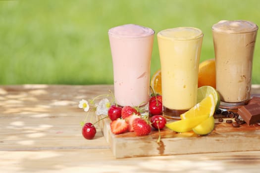 Three healthy smoothie milkshake drinks in tall glasses, natural tones