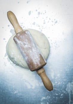 Preparing homemade Italian pizza with an overhead view of an old wooden rolling pin on flattened dough ready for the base or pie crust