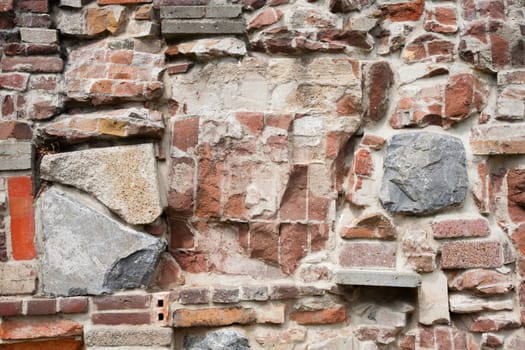Stone wall made of a variety of rocks and bricks.