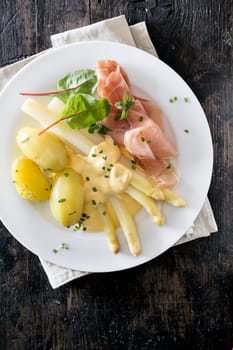 Serving of thinly sliced cured ham , asparagus spears and potatoes topped with mayonnaise and fresh herbs, overhead view