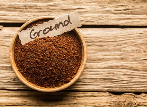 bowl full of ground coffee over an old wooden table