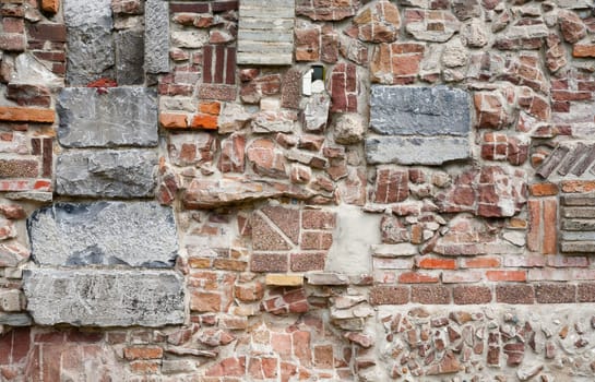 Stone wall made of a variety of rocks and bricks.