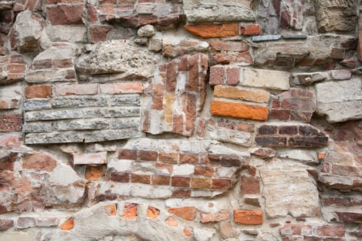 Stone wall made of a variety of rocks and bricks.