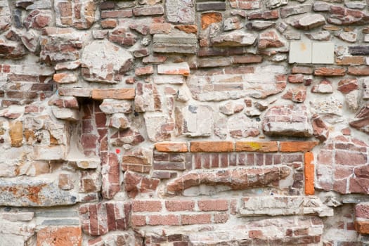 Stone wall made of a variety of rocks and bricks.