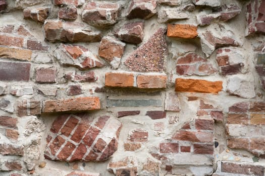 Stone wall made of a variety of rocks and bricks.