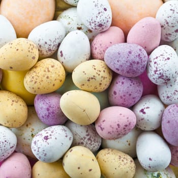 Background of colorful candies in the shape of eggs for Easter